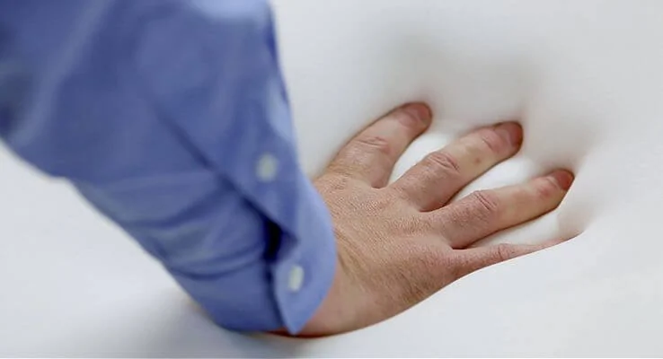 hand pushing into memory foam mattress
