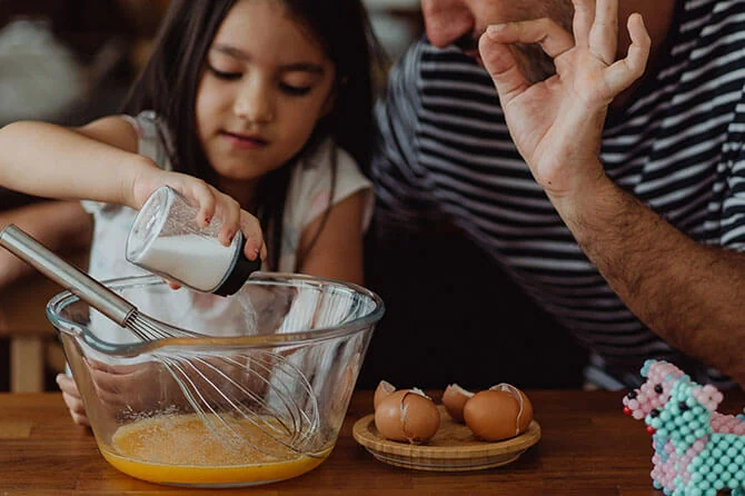Child baking in the kitchen with a parent