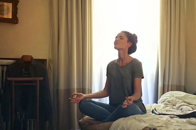 woman meditating on her bed