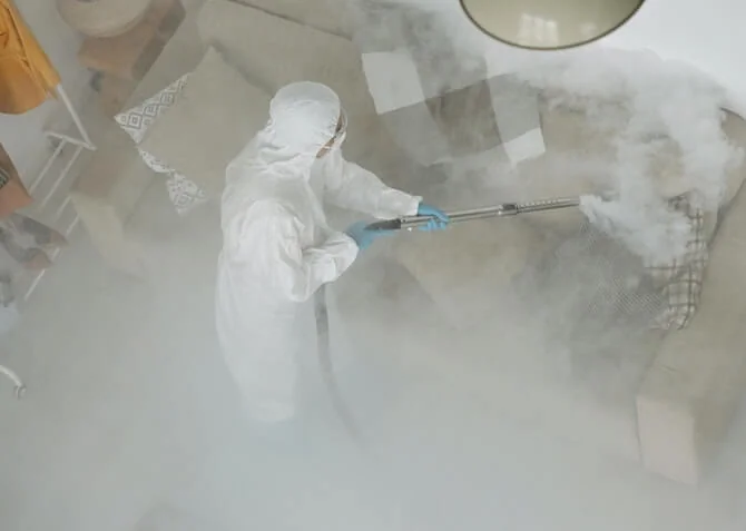 person in overalls fumigating a house