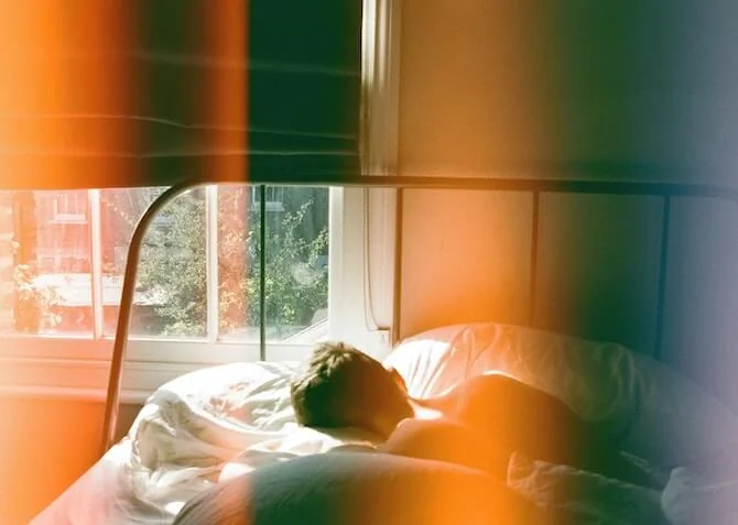man sleeping in bed with daylight coming through the curtains