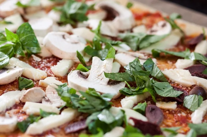 A pizza, topped with mushrooms and basil