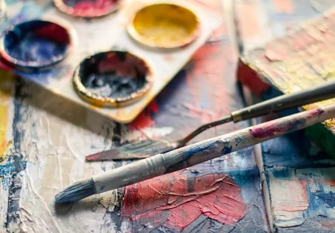 well-used paint brush next to palette