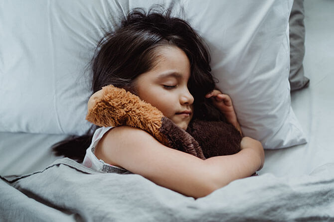 child sleeping soundly with a teddy bear