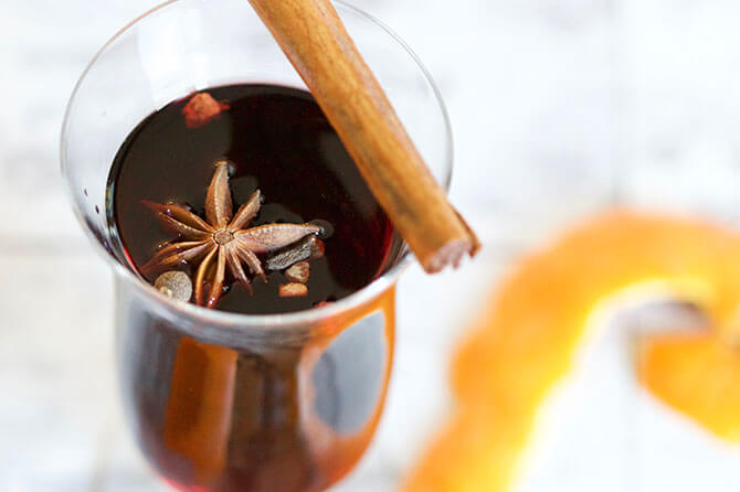Mulled wine in a glass mug, topped with a cinnamon stick