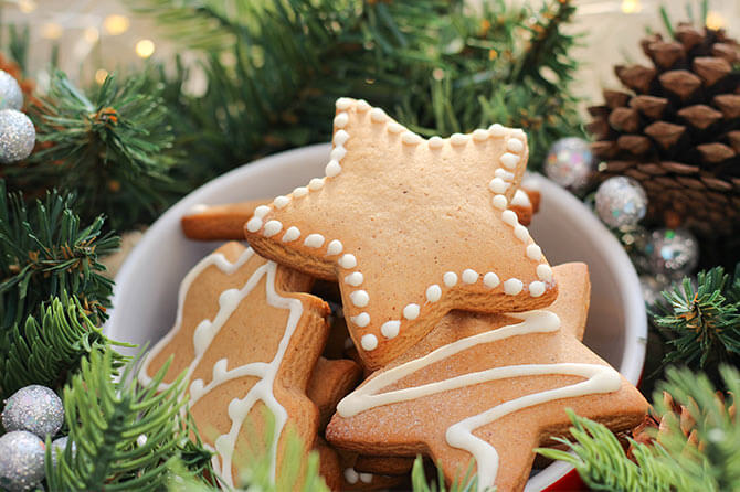Star-shaped biscuits in a bowl, surrounded by pinecones and tree branches