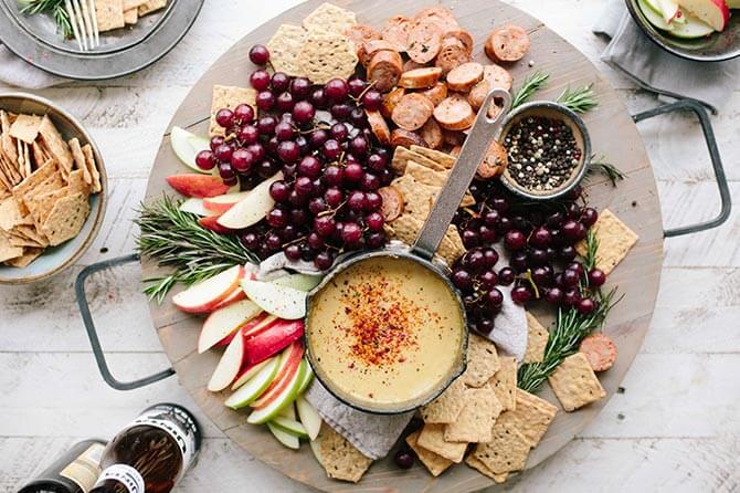 A seasonal charcuterie board filled with berries, fruit, crackers, and cheese