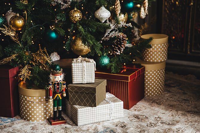 A toy soldier standing in front of gifts stacked beneath a tree