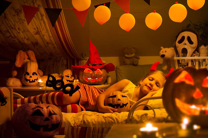 Child sleeping soundly in Halloween-themed bedroom
