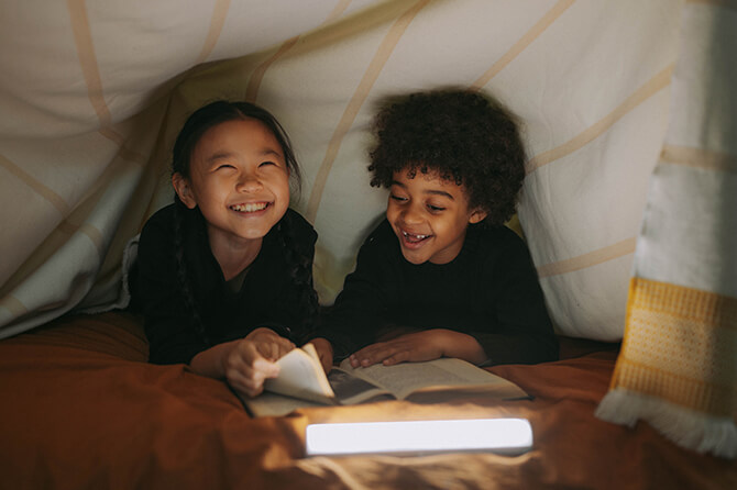 Children reading underneath a duvet