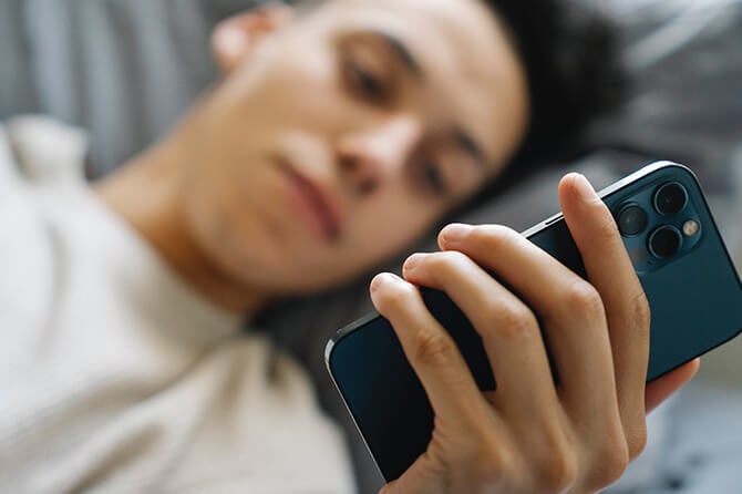 Man on phone whilst lying in bed