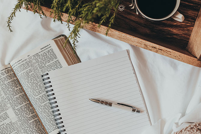 A notebook and a pen on a cosy-looking duvet