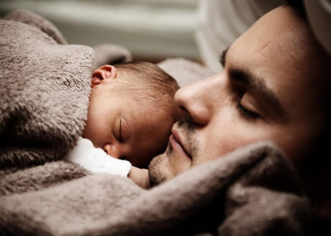 dad and baby sleeping in a blanket