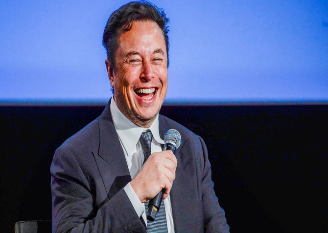 Elon Musk laughing down a microphone