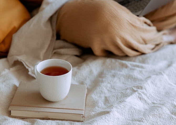 hot drink resting on a book in a bed