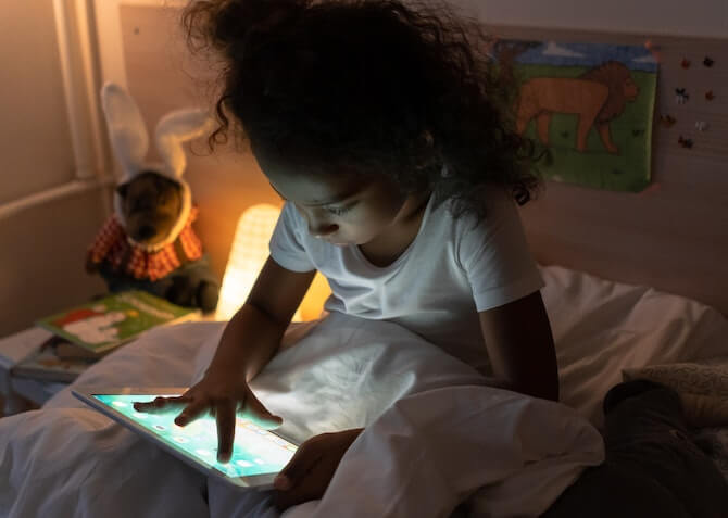 kid with tablet in bed at night