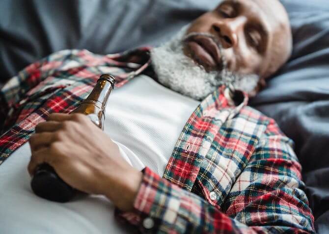 man sleeping with a bottle of beer in his hand