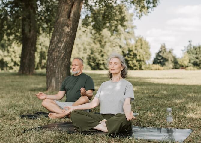 older couple meditating in the park