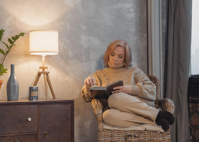 older woman reading a book in a comfy chair