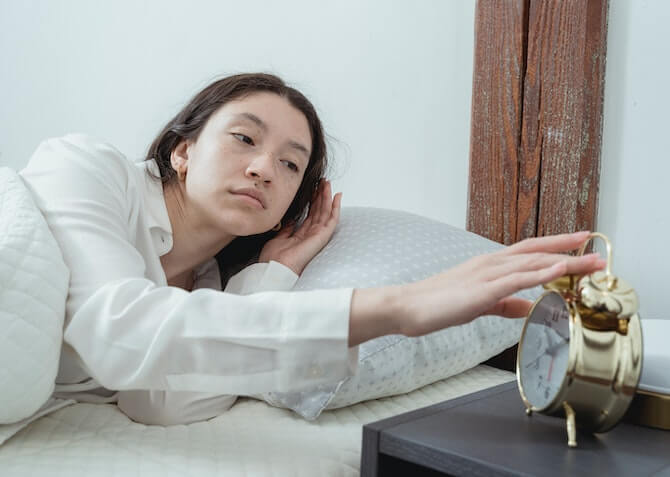 woman oversleeping with an alarm clock