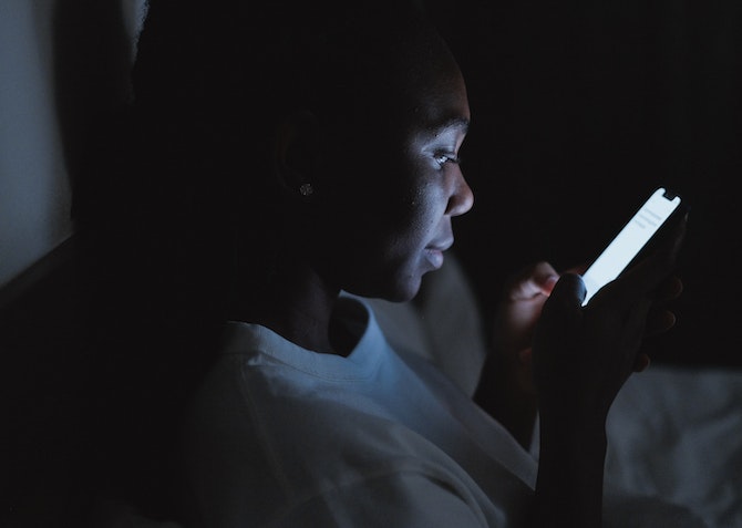 man using phone at night in bed