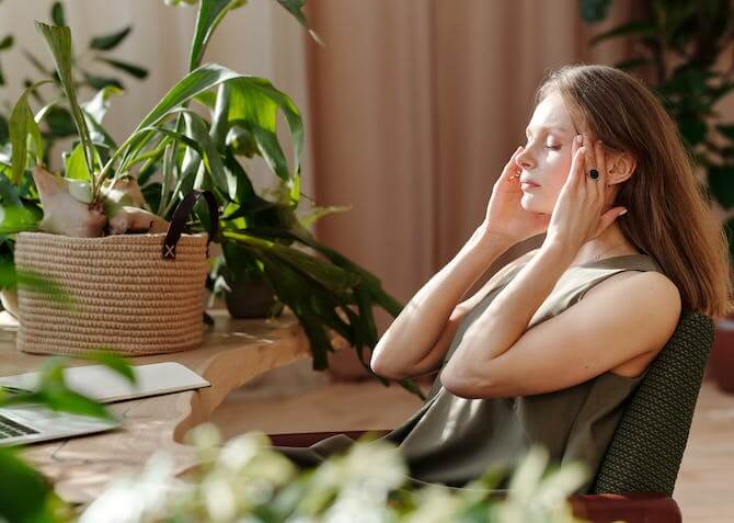 woman soothing a headache in a room with plants