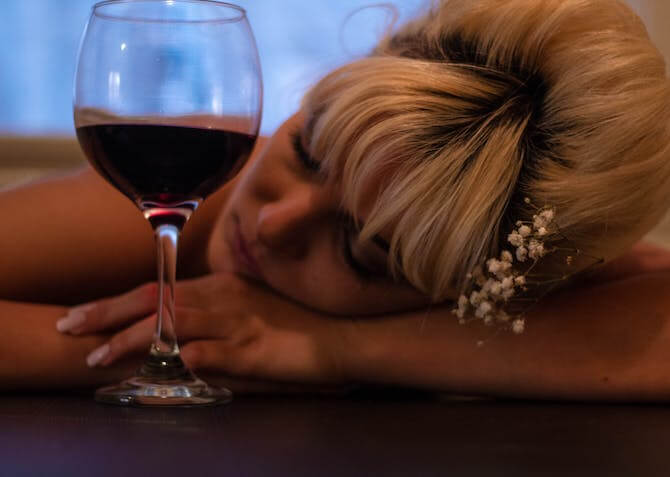 woman at a wedding sleeping next to her glass of red wine