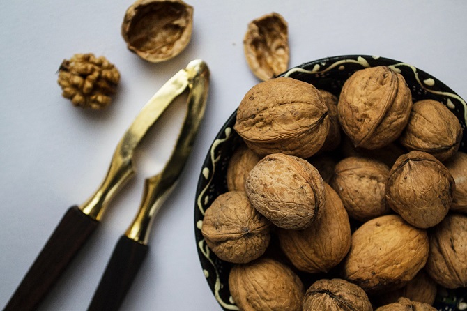 A bowl of walnuts, sat next to a nutcracker