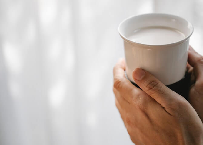 woman's hands holding a mug of hot milk