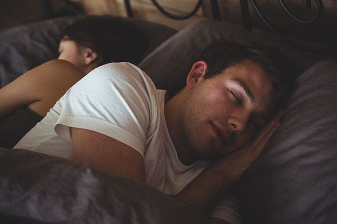 Couple sleeping beneath duvet