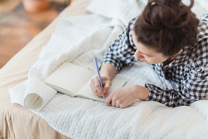 Girl journaling in bed