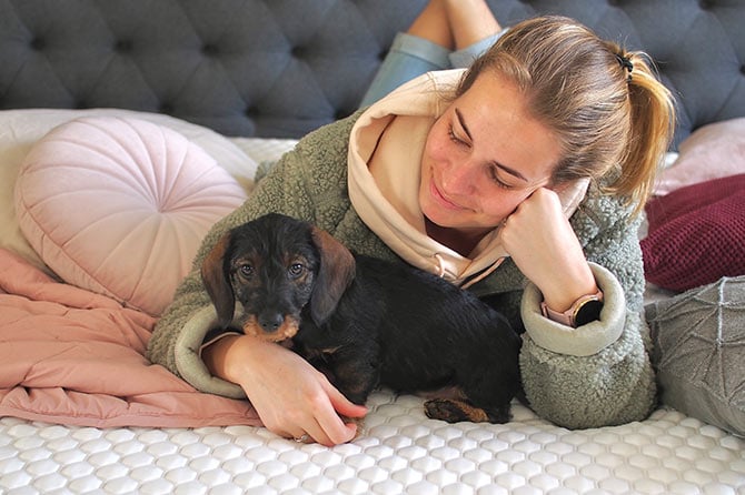Woman and dog cuddling on bed